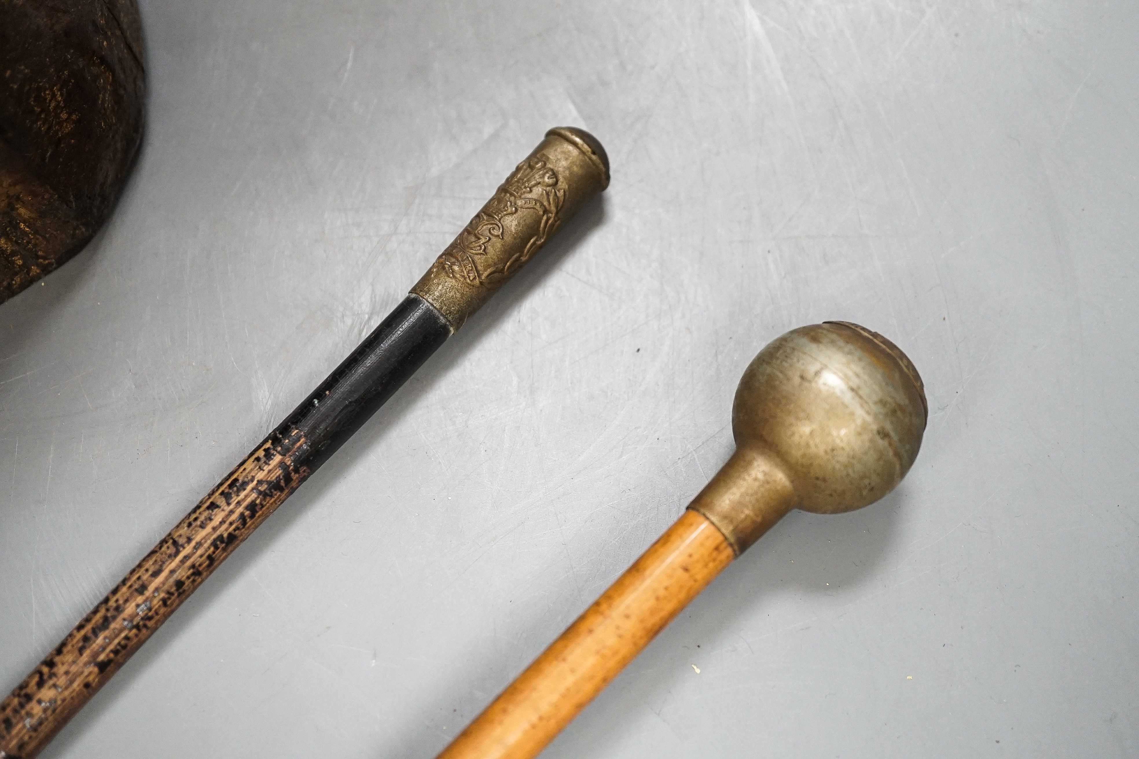 A group of WWI and WWII militaria badges, buttons, two swagger sticks, a Third Reich armband and a World War I German POW inscribed plaster ornament, longest swagger stick 70 cms long.